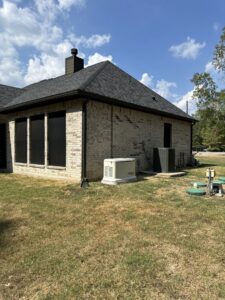 A Generac whole-home generator professionally installed next to a brick house by Never Without Power Generators LLC in Huffman, TX.