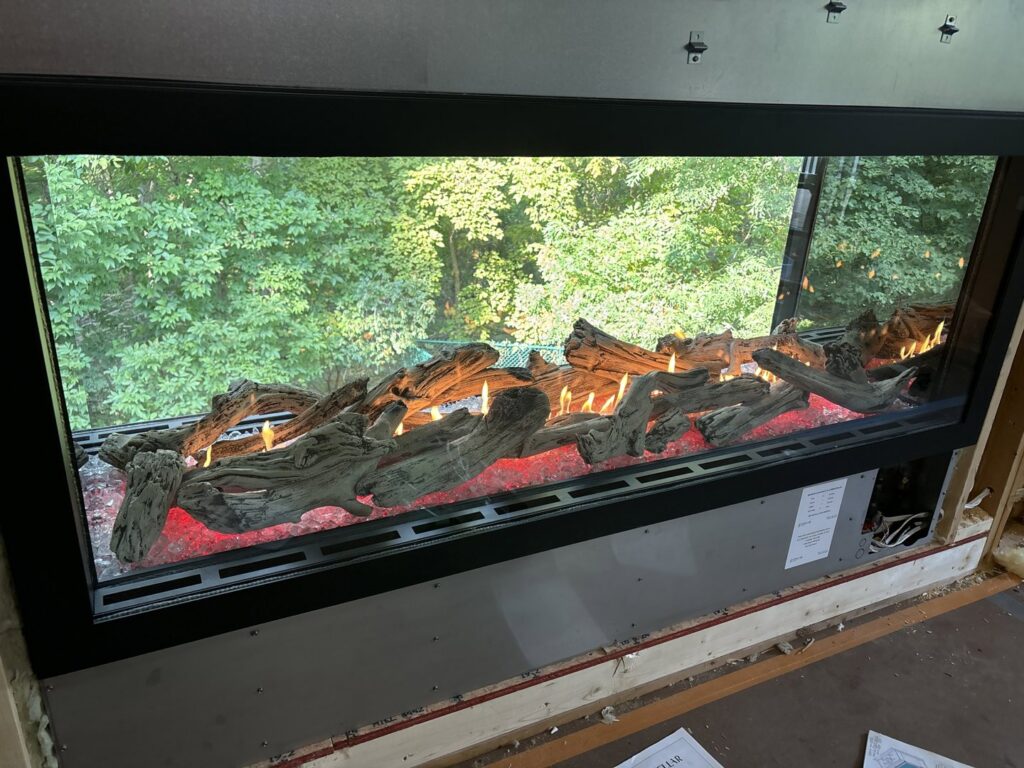 A wide electric fireplace insert with realistic logs and flames, expertly installed by Spartan Heating, Cooling and Fireplaces in Cedar Rapids, IA