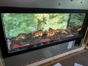 A wide electric fireplace insert with realistic logs and flames, expertly installed by Spartan Heating, Cooling and Fireplaces in Cedar Rapids, IA