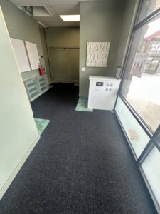 A wide view of a commercial hallway with new dark grey carpet installed by Bonsai Flooring in Spanish Fork, UT.