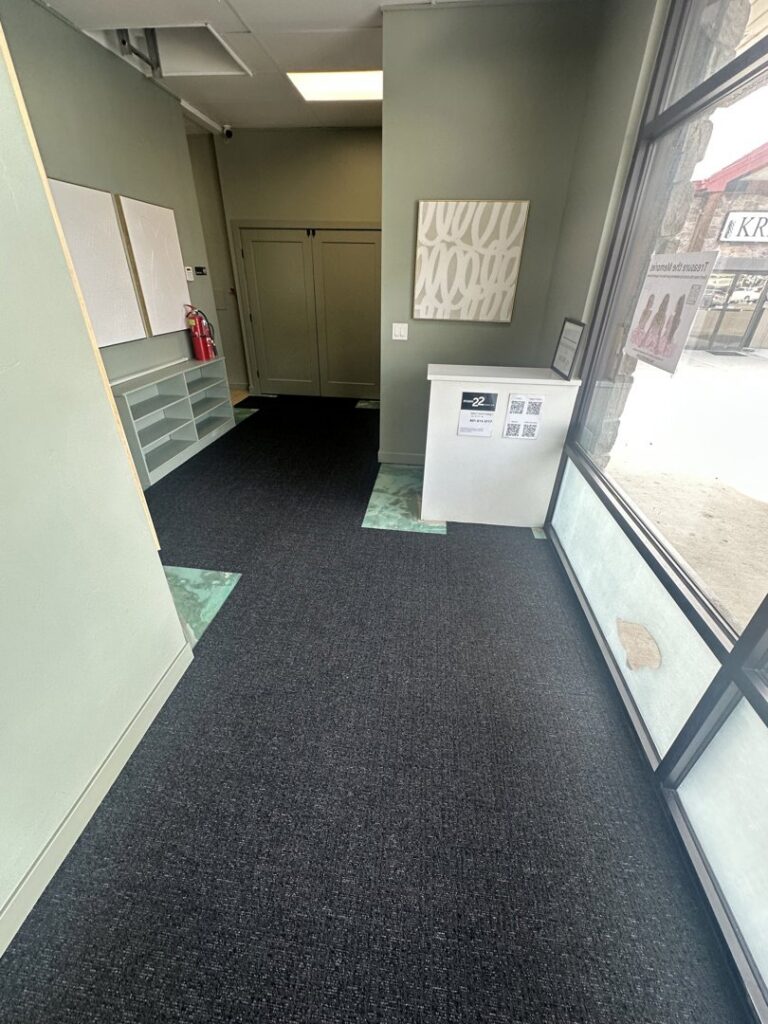 A wide view of a commercial hallway with new dark grey carpet installed by Bonsai Flooring in Spanish Fork, UT.