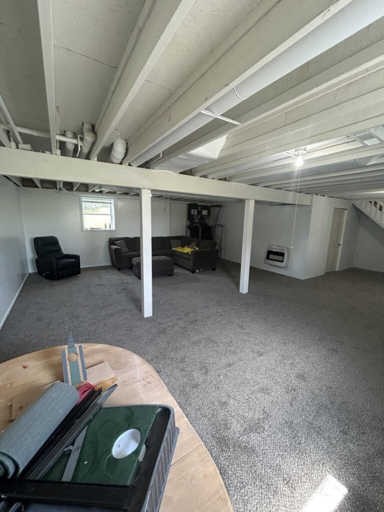 A wide view of a finished basement showcasing new gray carpet installed by Wilkins Floorcovering in Livonia, MI