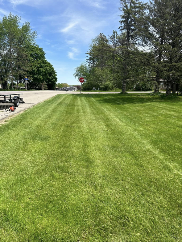 A wide view of a perfectly mowed lawn with stripes and an equipment trailer by J&C Lawn Care Service in Madison, WI.