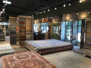 A wide interior view of the rug showroom at David Alan Rugs in Austin, TX, showcasing various rug displays and stacks.