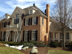 Wildlife control technicians on ladders accessing a roof for animal exclusion or removal by Wildlife Extractors in Bridgewater, MA.