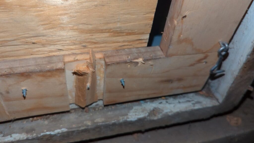 Damaged wood framing, likely caused by wildlife gnawing or scratching, requiring repair by Critter Control of Omaha, NE