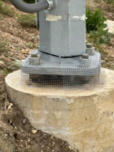 Wire mesh installed around the base of a metal pole for wildlife exclusion by Drapers Pest Management in Fort Worth, TX.