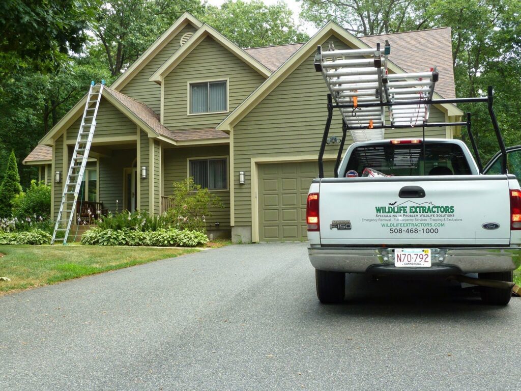 A Wildlife Extractors truck with a ladder parked at a residential home, ready for a pest control job in Bridgewater, MA.