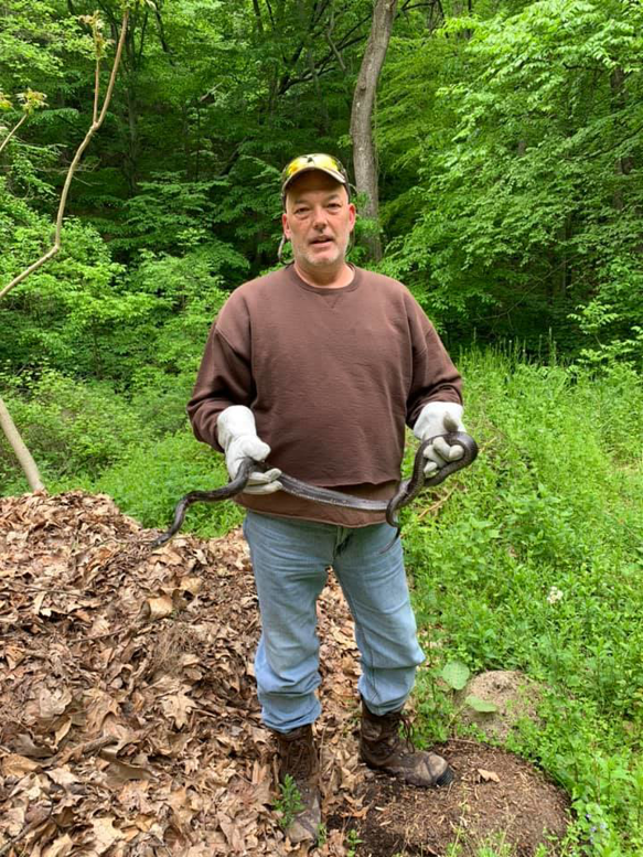 A wildlife professional from Nuisance Wildlife in Palmetto, FL, wearing gloves and holding a captured snake.