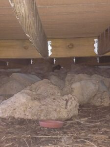 An inspection of a cluttered space under a deck, revealing potential wildlife activity, by Kansas Wildlife Pros in Wichita, KS.