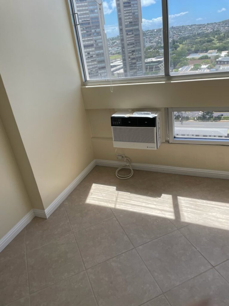 A window AC unit installed high on a wall, demonstrating installation services by Ultimate Air Conditioning in Pearl City, HI