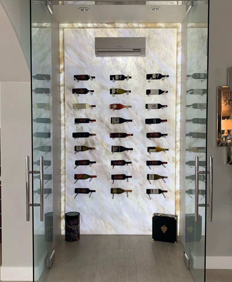 A mini-split air conditioning unit installed above a modern wine rack in a wine cellar by ProMasters HVAC Mechanical in New York, NY