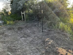 Wire fence with T-posts and a wooden post installed by Cowboy State Fencing LLC in Riverton, WY.