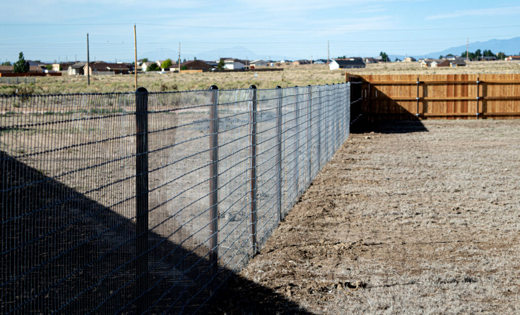 A wire mesh fence with wood posts and a wood privacy fence in the background by Fence Tech in Everett, WA.