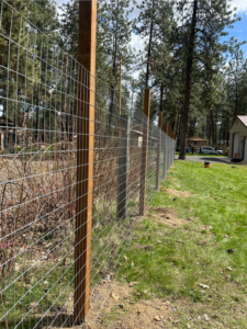 A wire mesh fence with sturdy wooden posts installed along a property by BKC Fencing in Spokane, WA.