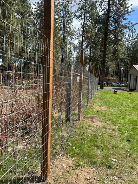 A wire mesh fence with sturdy wooden posts installed along a property by BKC Fencing in Spokane, WA.