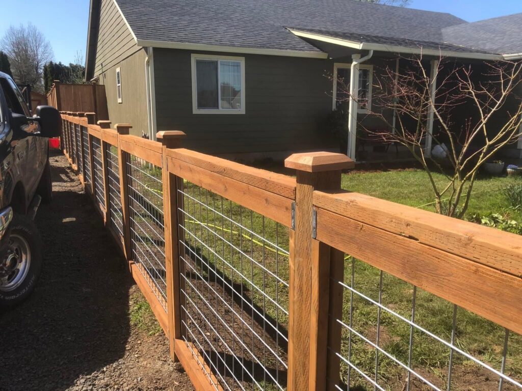A newly installed wire mesh fence with wooden posts and caps by Pacific Woods Fence and Deck in Springfield, OR.