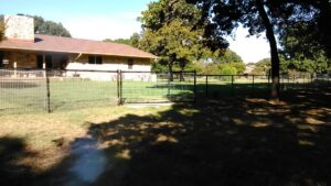 A wire mesh property fence with a gate installed by Dallas Mobile Welder, LLC. for a large residential area in Dallas, TX.