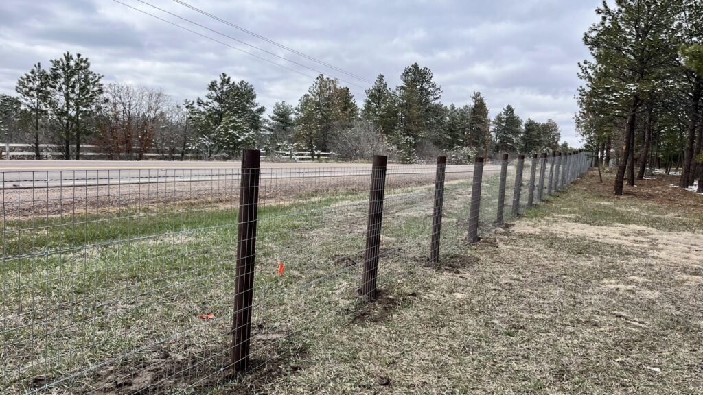 A wire mesh fence installed along a roadside by Supreme Fencing Denver, CO.