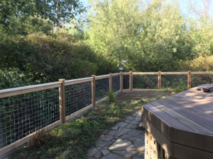 A wire mesh fence with a wooden frame next to a patio, installed by Webb Fencing Pros in Seattle, WA.
