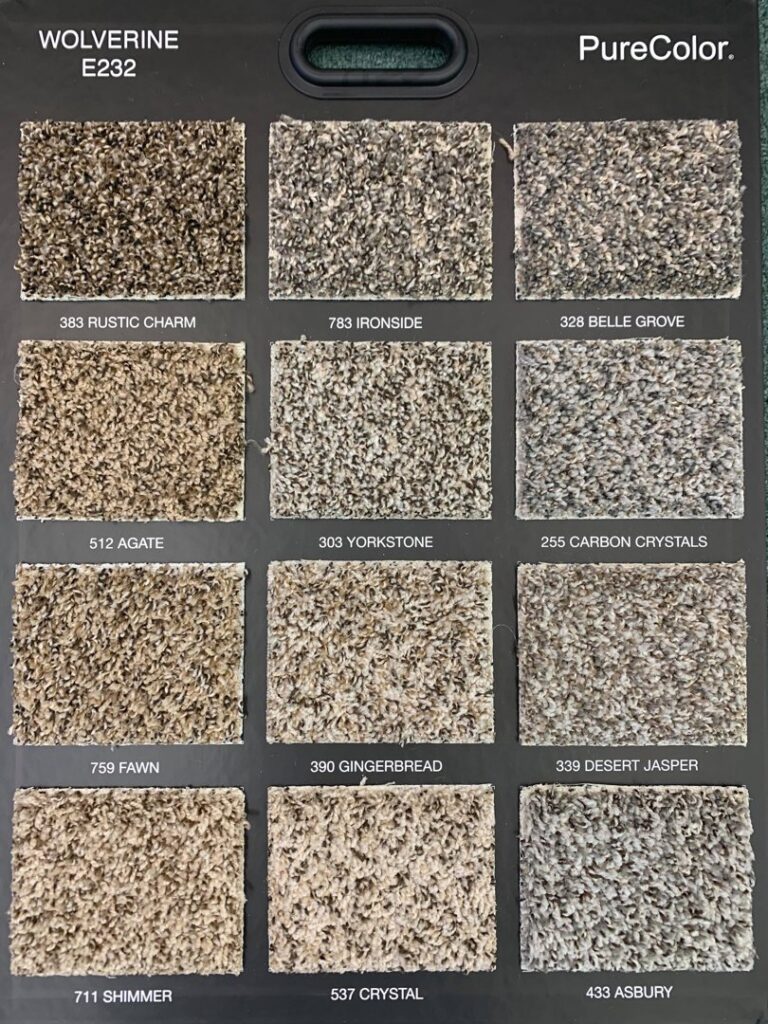 A display board showcasing various "Wolverine" carpet samples from PureColor, available at Rojas Carpet and Flooring in Denver, CO.