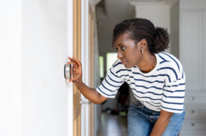 A woman adjusting a smart thermostat, representing HVAC control services from Cleveland Air Comfort in Solon, OH.