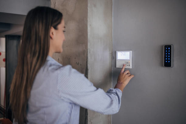A woman adjusting a modern wall-mounted thermostat, showcasing HVAC control services from Joe Logan HVAC in Dayton, OH.