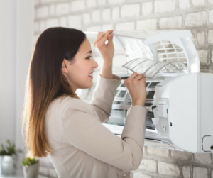 A woman cleaning the filter of a mini-split AC unit, a common HVAC maintenance task by MBI Heating and Air Conditioning in Allentown, PA.