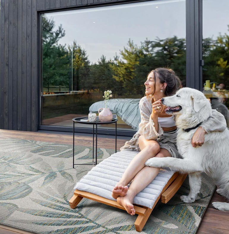 A woman and her dog relaxing on an outdoor deck with a stylish leaf-patterned rug from Adiva Rugs in Chicago, IL.