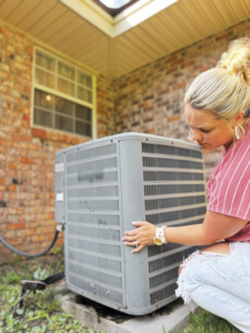 A woman inspecting an outdoor AC unit, representing HVAC service from Rightway Heating & Air in Columbus, OH.