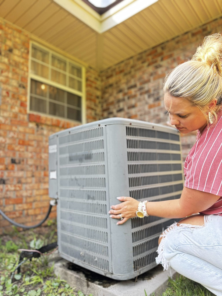 A woman inspecting an outdoor AC unit, representing HVAC service from Rightway Heating & Air in Columbus, OH.