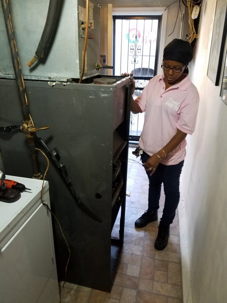 A Daniels HVAC woman technician servicing a furnace in Philadelphia, PA.