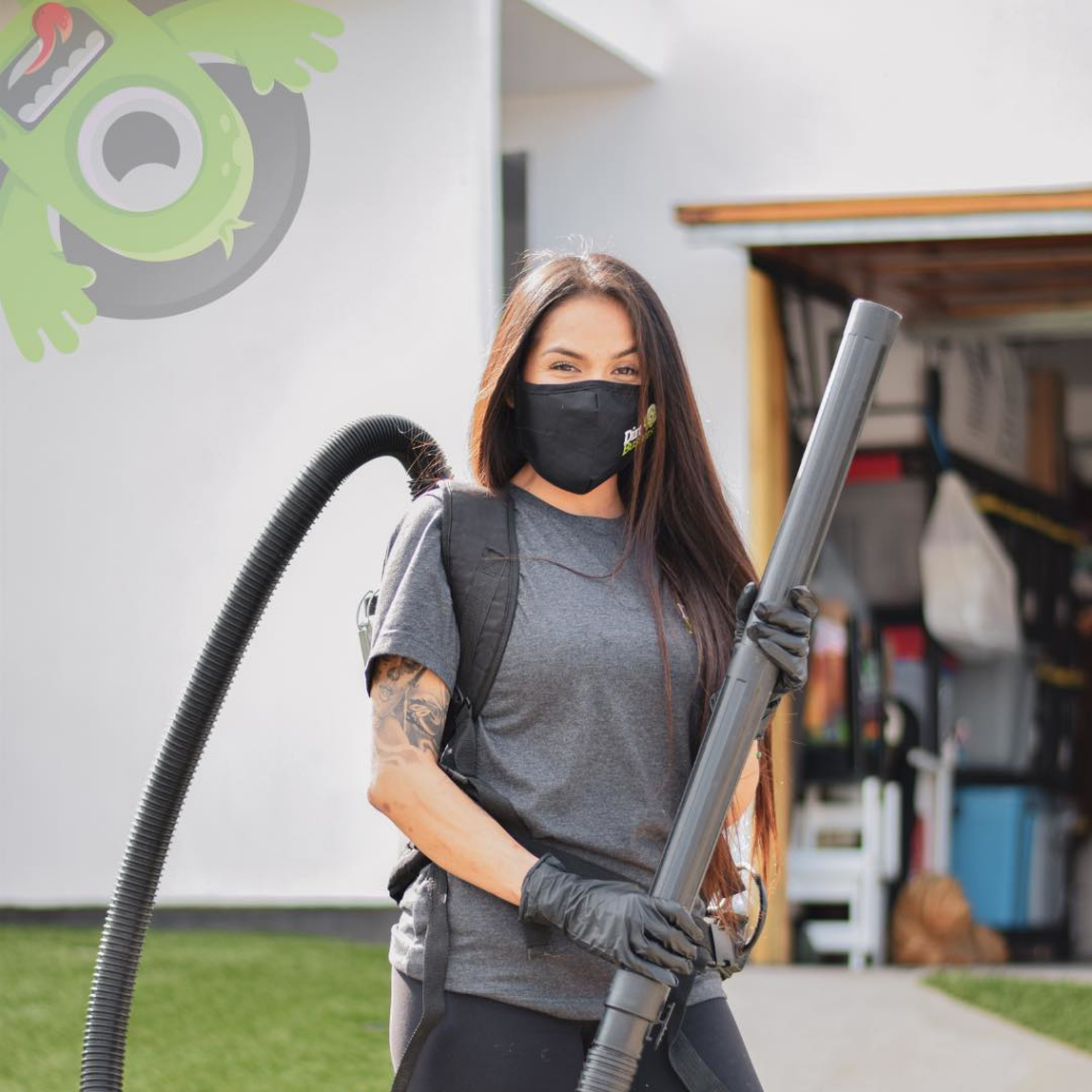 A Dirt Busters, Inc. team member in Anaheim, CA, wearing a mask and holding a backpack vacuum cleaner, ready for service.