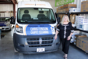 A woman stands proudly in front of a Christenson Carpet Cleaning van in Hastings, NE.