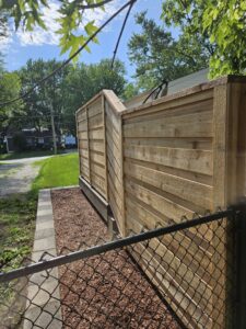 A combination of a new wooden privacy fence and existing chain-link fence by JM Fence Works in Davenport, IA.