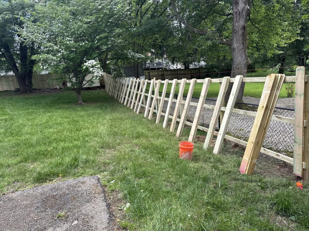 A wood and chain link fence installation in progress in a backyard by KY Fencing Unlimited in Louisville, KY.