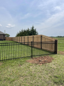 A new installation featuring a combination of wood and black metal fencing by Fence Restorations LLC in Ponca City, OK.