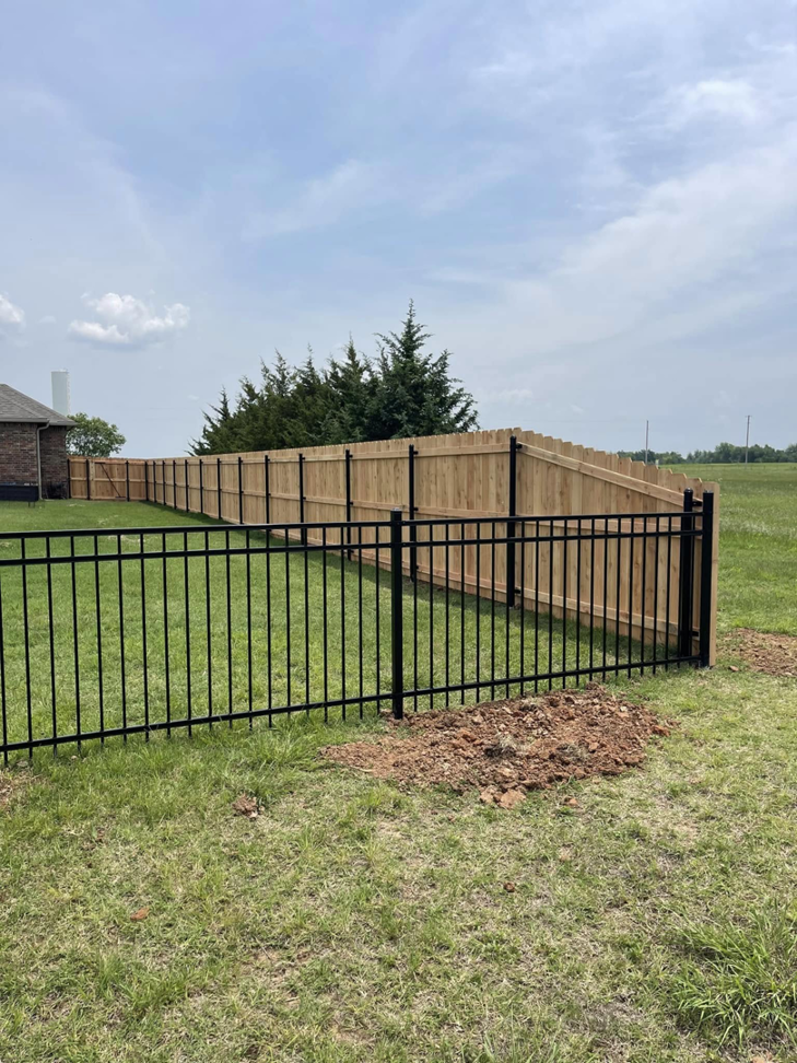A new installation featuring a combination of wood and black metal fencing by Fence Restorations LLC in Ponca City, OK.