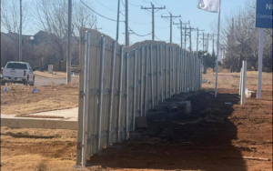 A wood and metal fence installation in progress along a roadside by KY Fencing Unlimited in Louisville, KY.