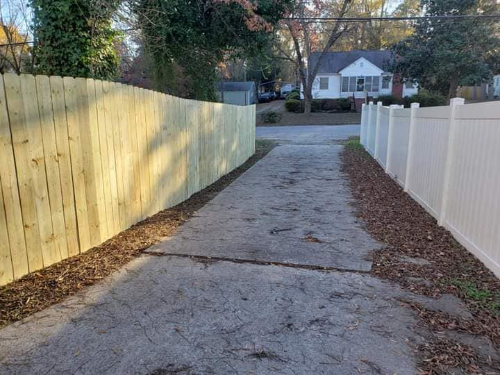 A driveway flanked by a new wood privacy fence on one side and a white vinyl fence on the other, installed by The Fence Guy One in Greenville, SC.