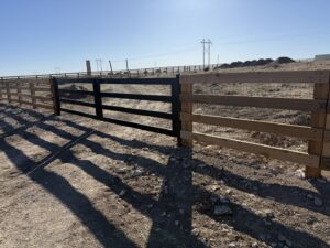A wood and wire fence with a black gate installed by Pueblo Fence Co in Pueblo West, CO.