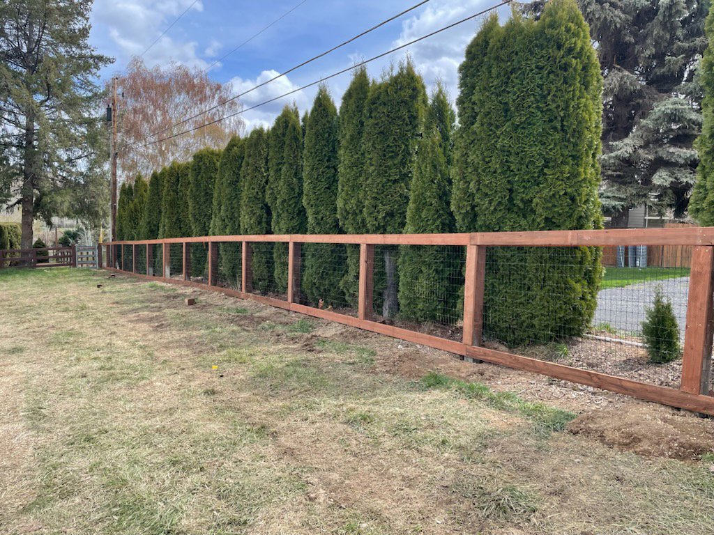 A wood and wire mesh fence installed along a property line by Integrity Gates and Fencing in Yakima, WA