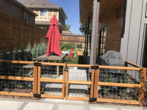 A custom wood and wire mesh fence with a gate, perfect for pet enclosures or garden areas, installed by Fence Guru LLC in Denver, CO.