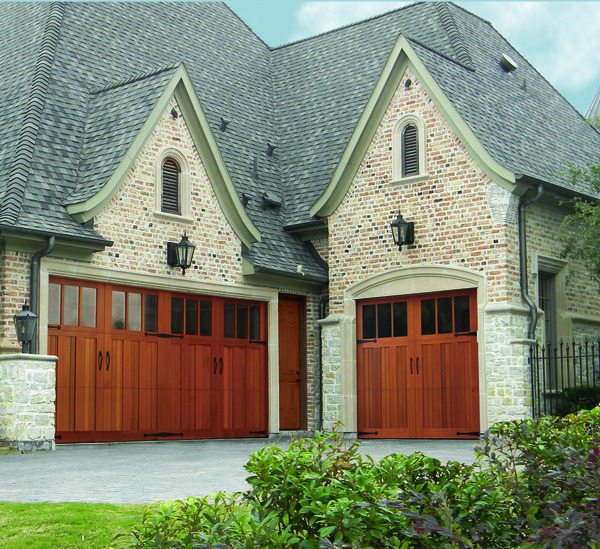 Wood carriage-style garage doors with windows on a brick home by Overhead Door Company of the Great Plains in Lawton, OK.