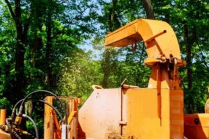 A wood chipper in full operation, processing branches into chips for Greener Grounds Lawn and Tree in Birmingham, AL