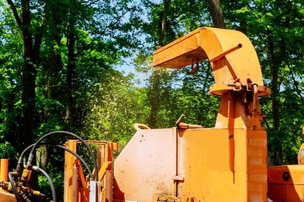 A wood chipper in full operation, processing branches into chips for Greener Grounds Lawn and Tree in Birmingham, AL