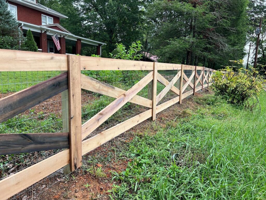 A newly installed wood cross-buck fence with wire mesh running alongside a road, built by 865 Fencing in Knoxville, TN.
