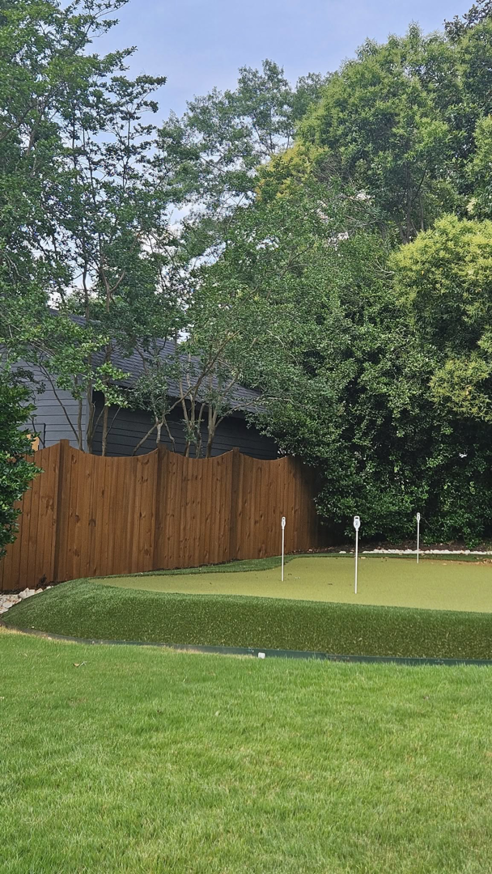 A sturdy wood fence providing privacy behind a backyard putting green, installed by The Fence Guy One in Greenville, SC.