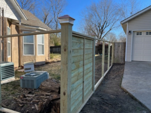 A wood fence under construction, showing posts and partially installed panels by Fence Solutions of NWA in Gravette, AR.