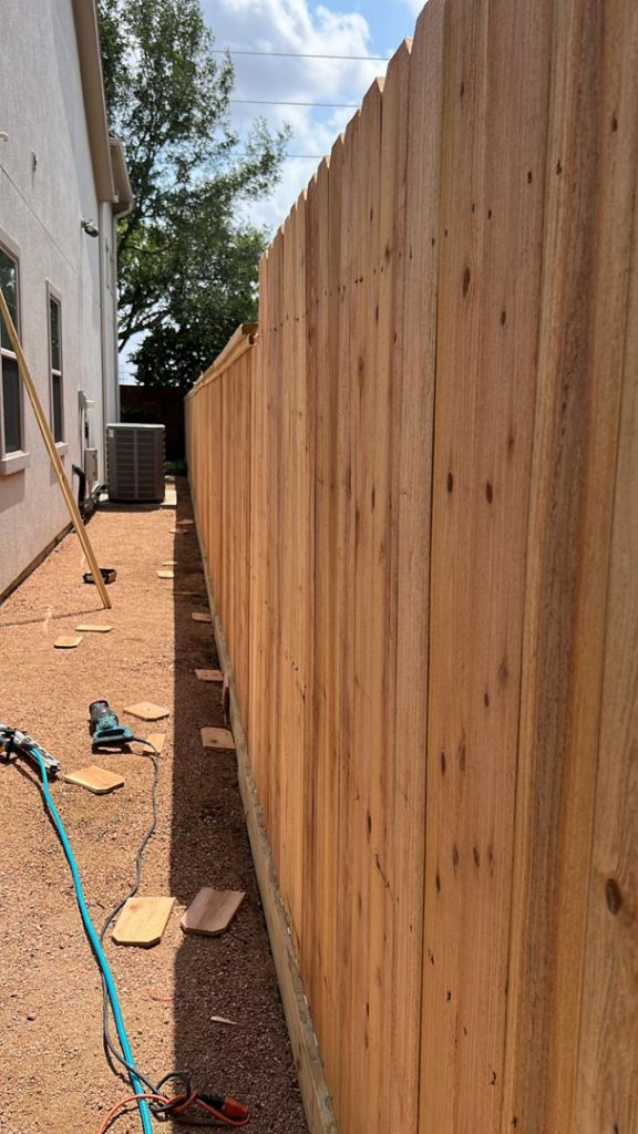 A wooden fence under construction with tools nearby, by Alexi's Handyman Services in Indianapolis, IN.
